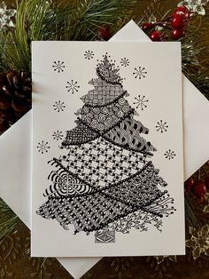 a christmas card with a black and white drawing of a tree on the front, surrounded by snowflakes