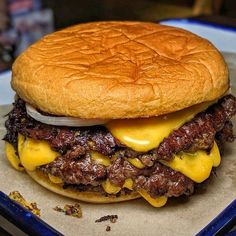 a cheeseburger with meat and onions on a bun is sitting on a tray