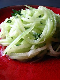 a red plate topped with sliced onions and herbs