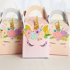 three boxes with unicorn ears and flowers on them, one has a handle for the top