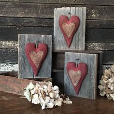 three wooden hearts are hanging on the wall next to shells and other items in front of them