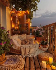 a balcony decorated with wicker furniture and flowers on the table, candles lite in the background