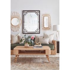 a living room with couches, tables and mirrors on the wall above them in front of a window