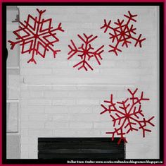 a white fireplace with red snowflakes hanging from it's mantle and on the mantel