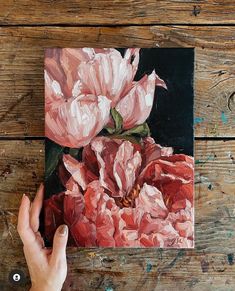 a person holding up a painting with pink flowers on it