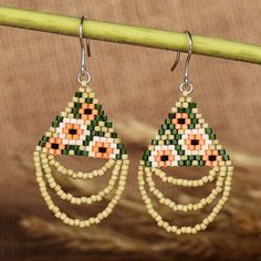 a pair of beaded earrings hanging from a wooden stick