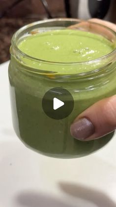 a hand holding a jar filled with green liquid