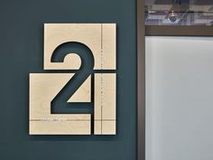 the number two is made out of wood and sits next to a wall mounted sign