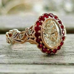 a fancy ring with red and white stones on it's side sitting on a wooden surface