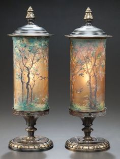 two vases sitting next to each other on top of a metal stand with trees painted on them