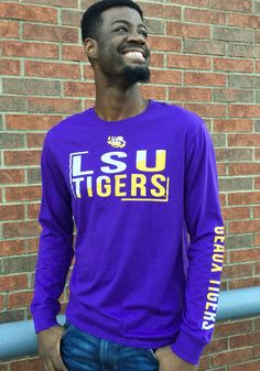 a man standing in front of a brick wall wearing a purple lsu long sleeve shirt