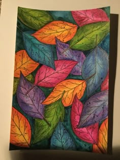 a painting of colorful leaves on a white surface