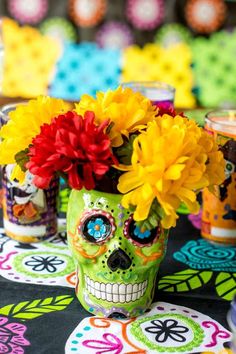 a green skull with flowers in it's head sitting on a colorful table cloth