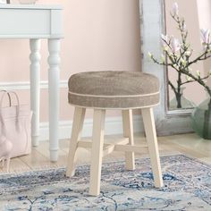 a white stool sitting on top of a rug in front of a table and mirror