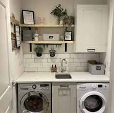 a washer and dryer in a small room with open shelves on the wall