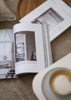 an open book sitting on top of a table next to a cup of coffee