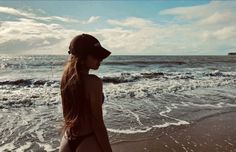 a woman standing on top of a beach next to the ocean