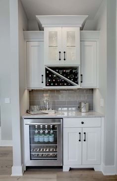 a kitchen with white cabinets and an open wine cooler in the middle of the room