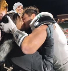 two men and a woman are kissing in front of a group of people wearing boxing gloves