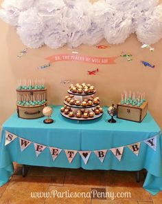 a blue table topped with cupcakes and cake next to a white paper cloud