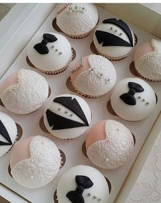 a box filled with cupcakes covered in white frosting and black fondant