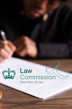 a person sitting at a table with a pen and paper in front of them that says law commission performing the law