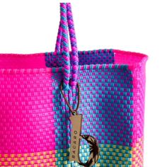 a pink and blue bag with a tag hanging from it's side on a white background