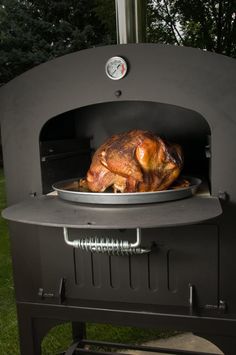 a turkey roasting in an outdoor oven with the lid open to show it's meat