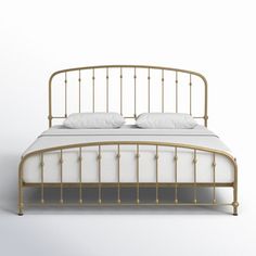 a bed with white sheets and gold headboard