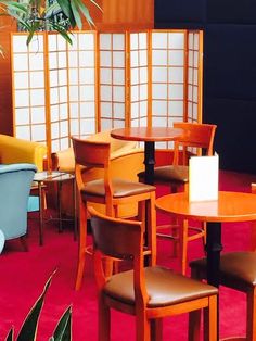 a room with chairs, tables and plants on the red carpeted floor in front of it