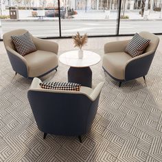 three chairs and a coffee table in an office lobby with large windows looking out onto the street