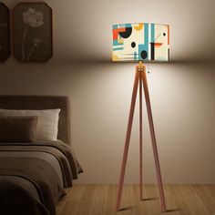 a lamp that is on top of a tripod in a room next to a bed