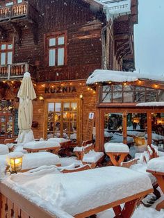 an outdoor restaurant covered in snow next to a building