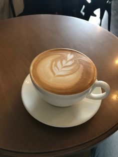 a cappuccino on a saucer sitting on a table