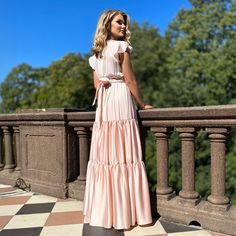 a woman in a pink dress standing on a balcony