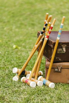 several wooden croquets sitting on top of an old suitcase in the grass