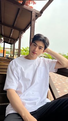 a young man sitting on top of a wooden bench