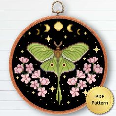 a cross stitch pattern with a moth and flowers in the center on a black background