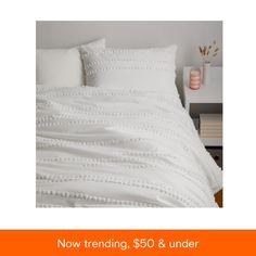 a bed with white sheets and pillows on top of it next to a night stand