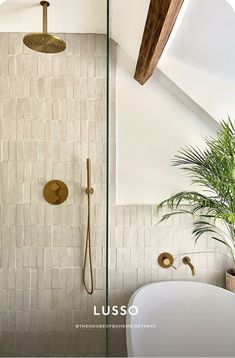 a bathroom with a tub, shower head and plants on the wall next to it