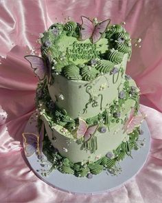 a three tiered cake with green frosting and butterflies