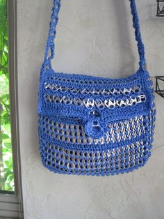 a blue crocheted purse hanging on the wall