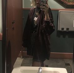 a woman taking a selfie in a bathroom mirror with her cell phone up to her ear