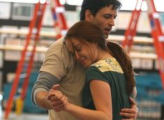 a man and woman dance together in an indoor area with red ladders behind them