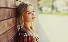 a young woman leaning against a brick wall