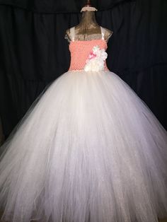 a white and pink flower girl dress on a mannequin head stand in front of a black backdrop