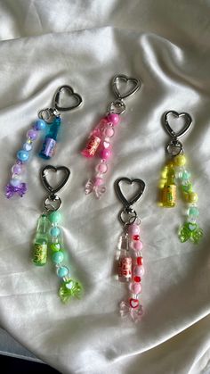 four key chains with charms in the shape of hearts and candy on top of a white sheet