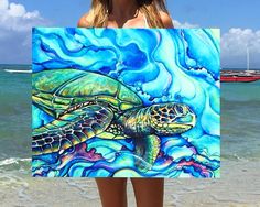 a woman standing on the beach with a painting of a turtle in front of her