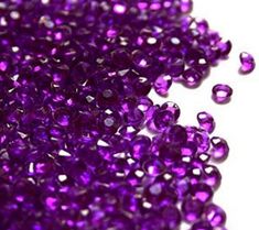 purple beads are scattered on a white surface