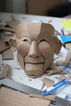 a cardboard mask sitting on top of a table next to scissors and other crafting supplies